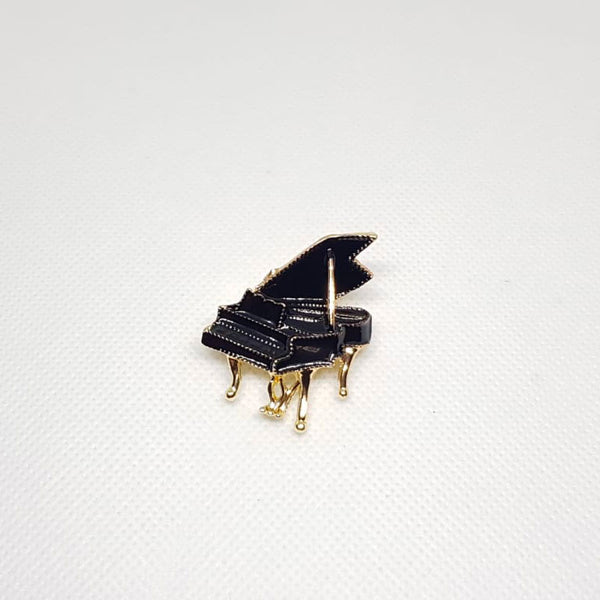 Broche dorée en forme de piano noir.