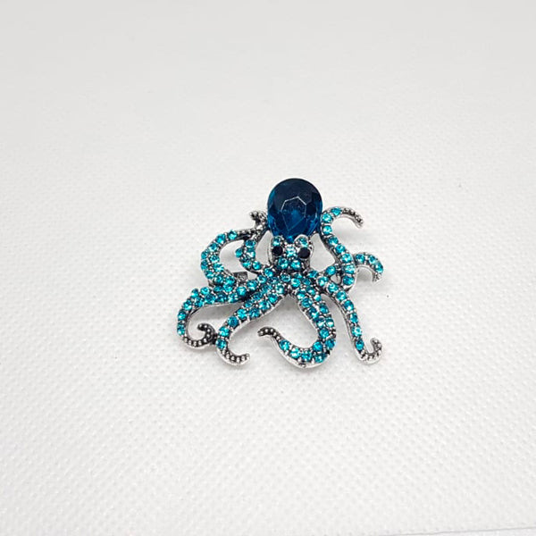 Broche argentée en forme de pieuvre de cristal bleue.