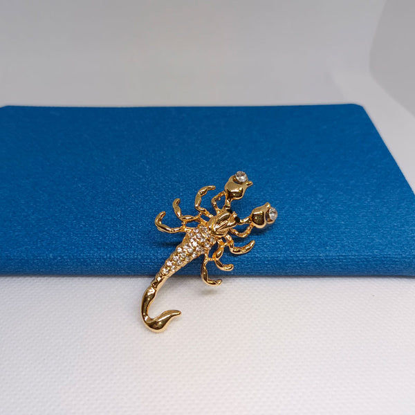 Broche dorée en forme de scorpion orné de cristal.